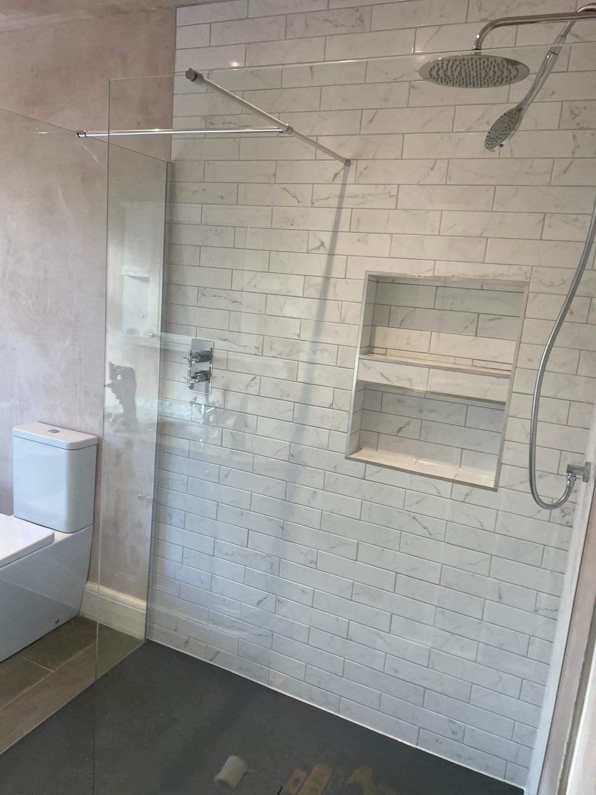 Walk-in shower with marble subway tiles and chrome fittings