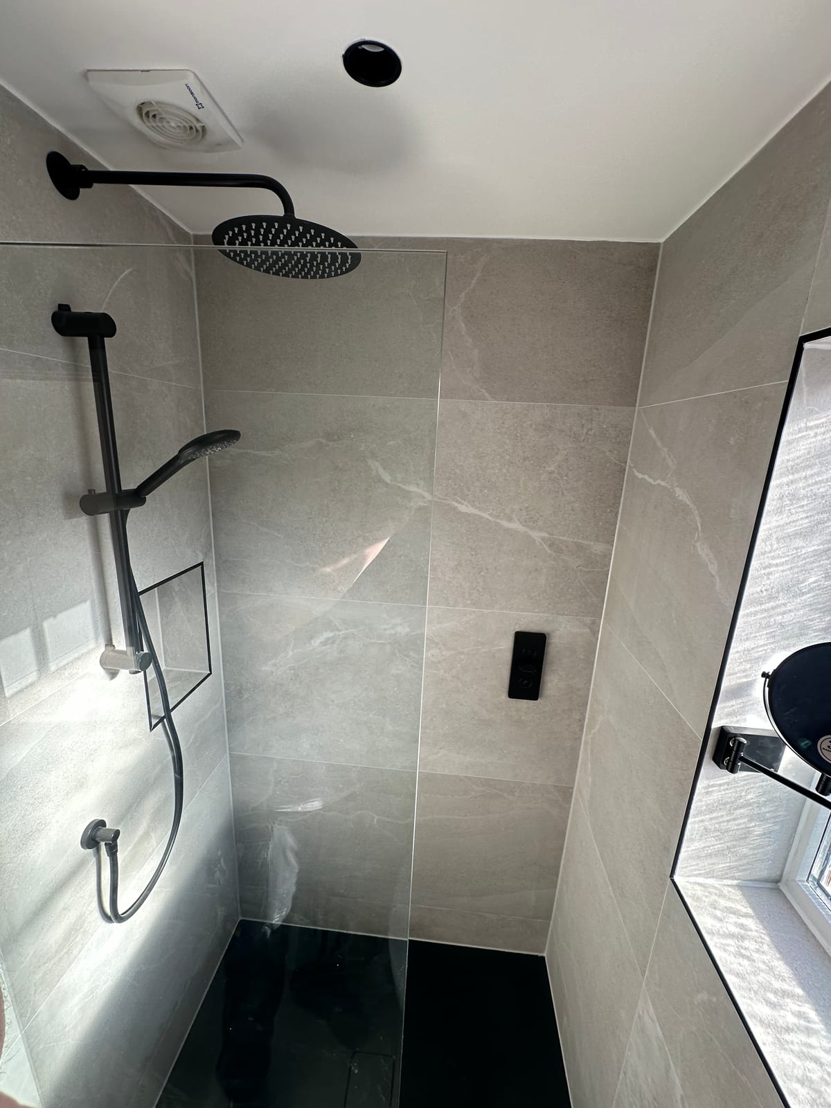 Modern walk-in shower with grey marble tiles and rainfall head