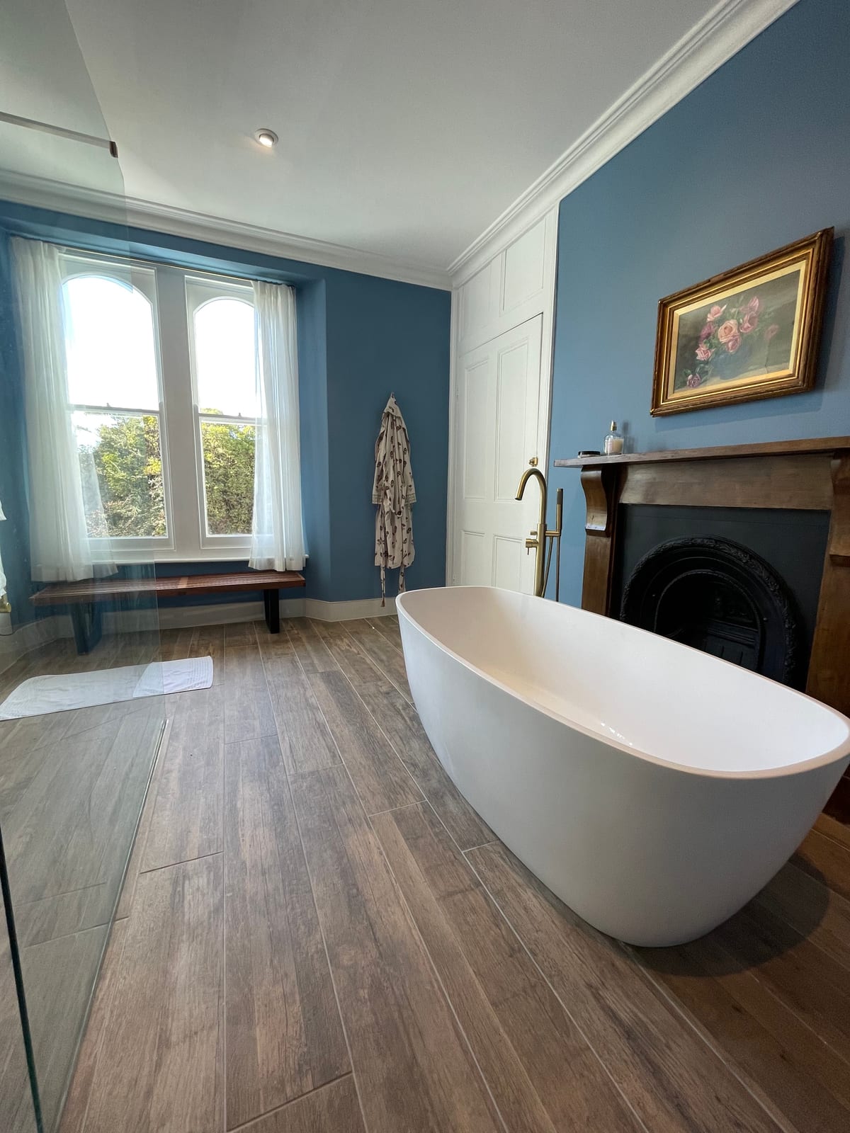 Luxury blue bathroom with freestanding bath and period fireplace