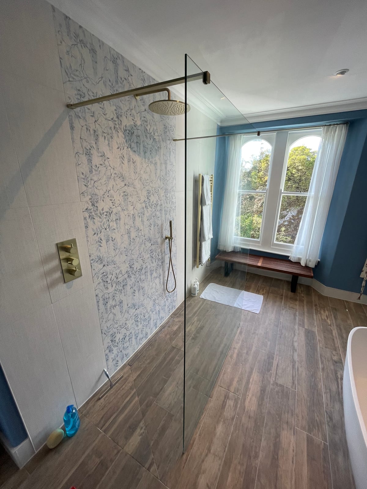 Walk-in shower with brushed gold fittings and decorative tile feature