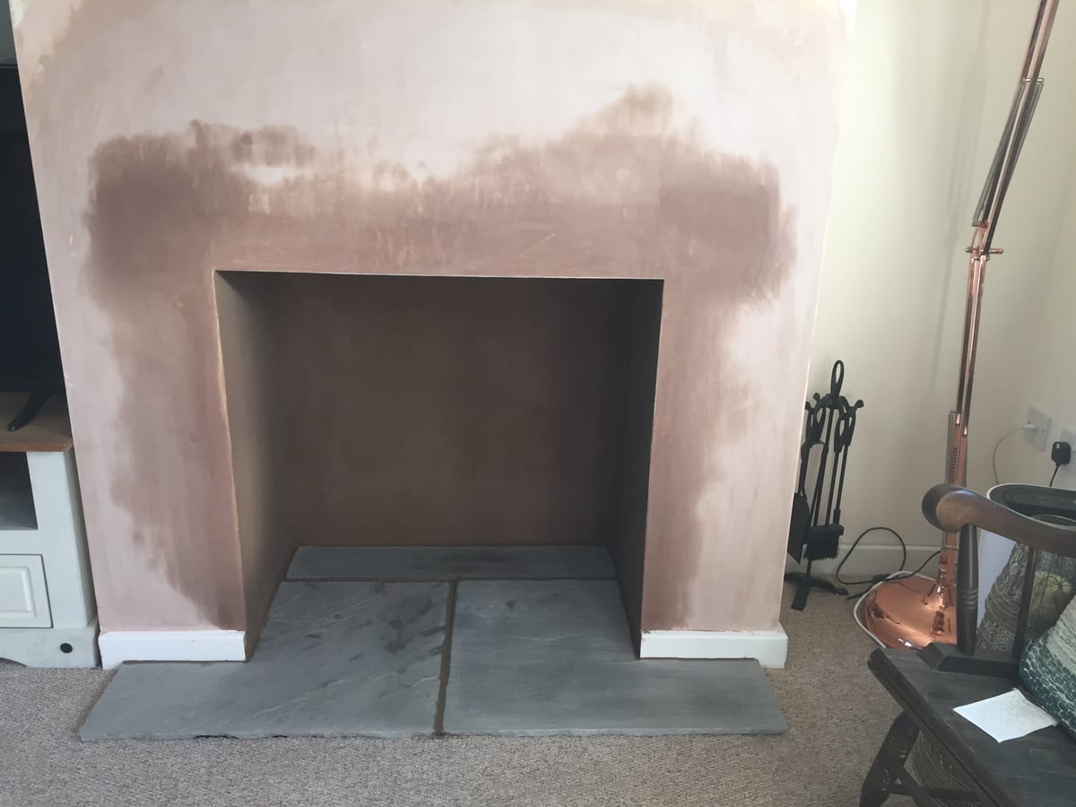 Freshly plastered chimney breast with new stone hearth